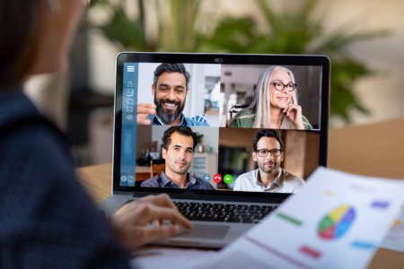 Back view of business woman talking to her colleagues about business plan in a video conference call online meeting.