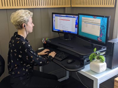 Working from home, typist sitting at their desk, hands on keyboard, headset in ears, listening to an audio file and typing into a word document.